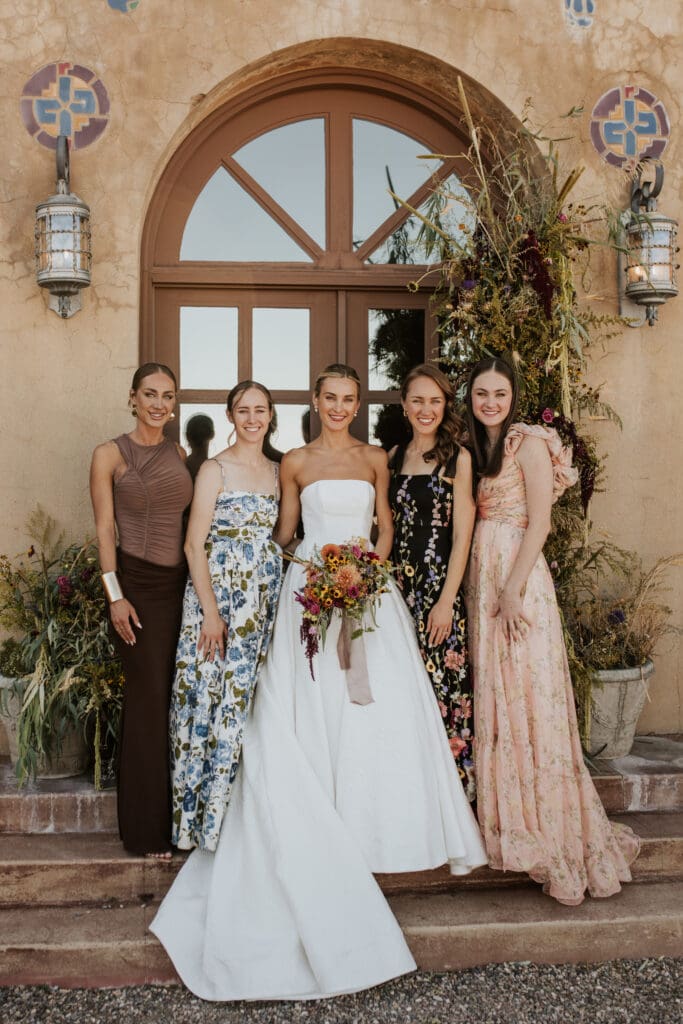 bride and her sisters standing on a step with. floral backdrop