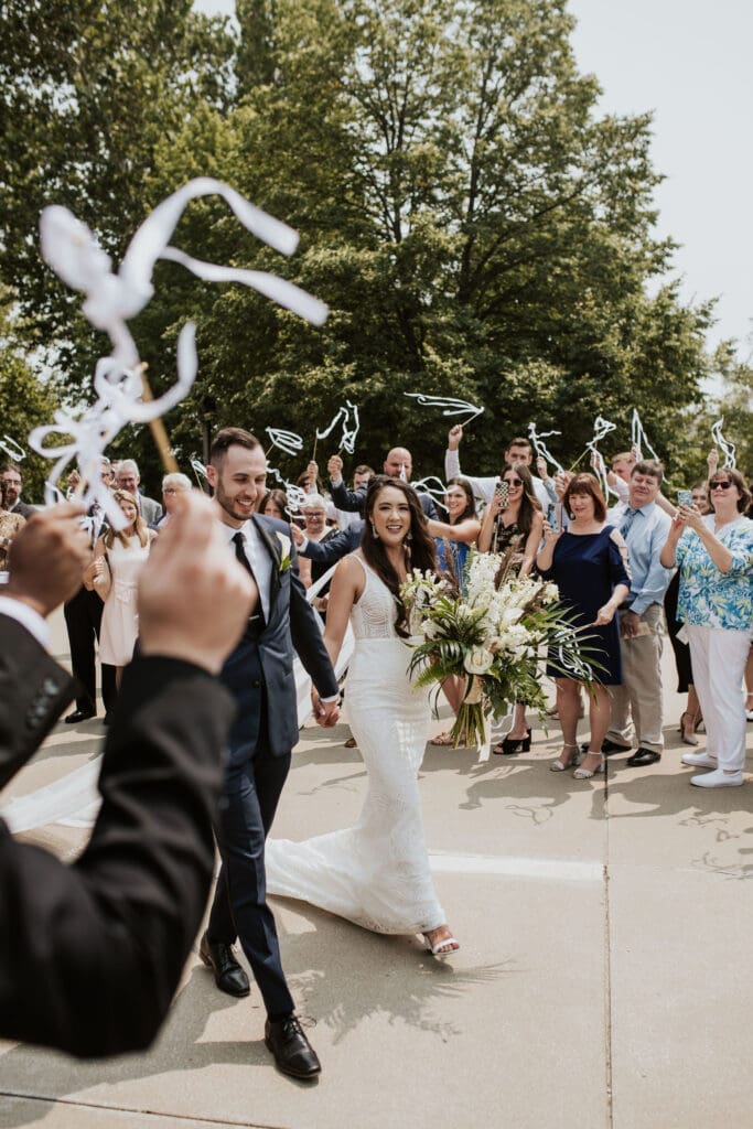 Wedding guests waving ribbon wands as a Catholic couple exits their parish