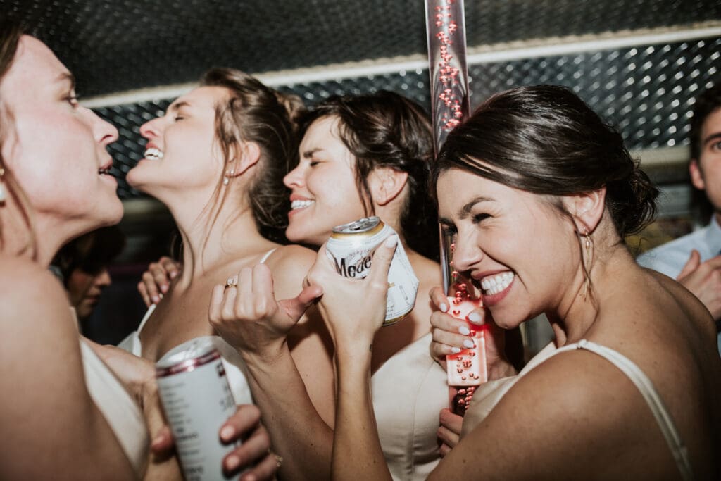 bride and bridesmaids dancing with beer on a party bus