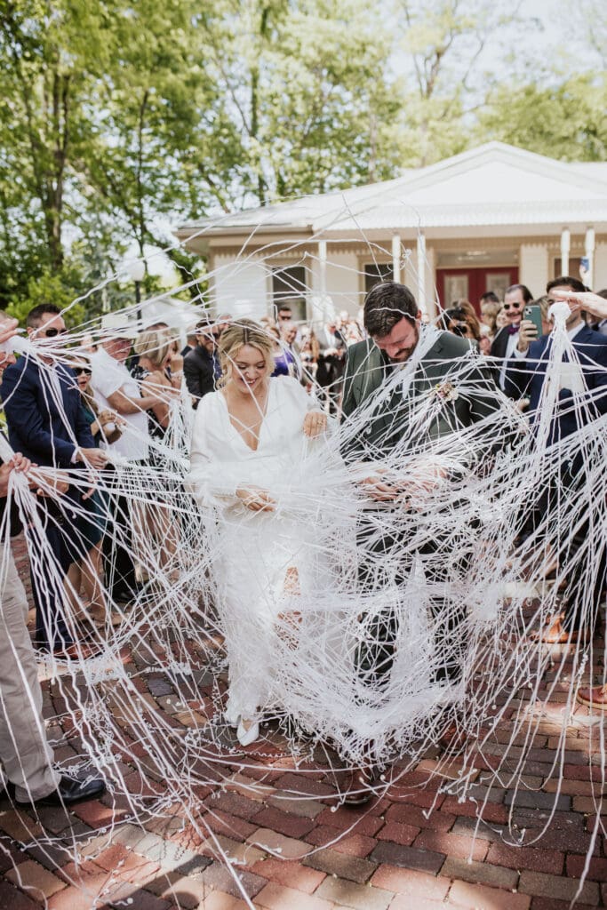 Wedding guests waving streamers as a joyful couple exits the church