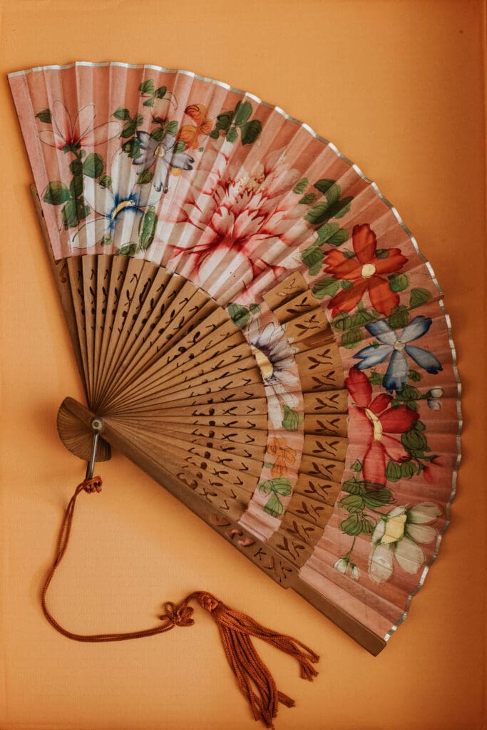 a floral hand fan on an orange background