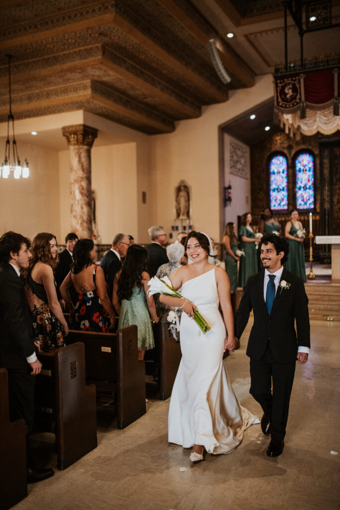 Bride and Groom walking out smiling after their wedding ceremony in Gesu Catholic Church in Detroit Michigan