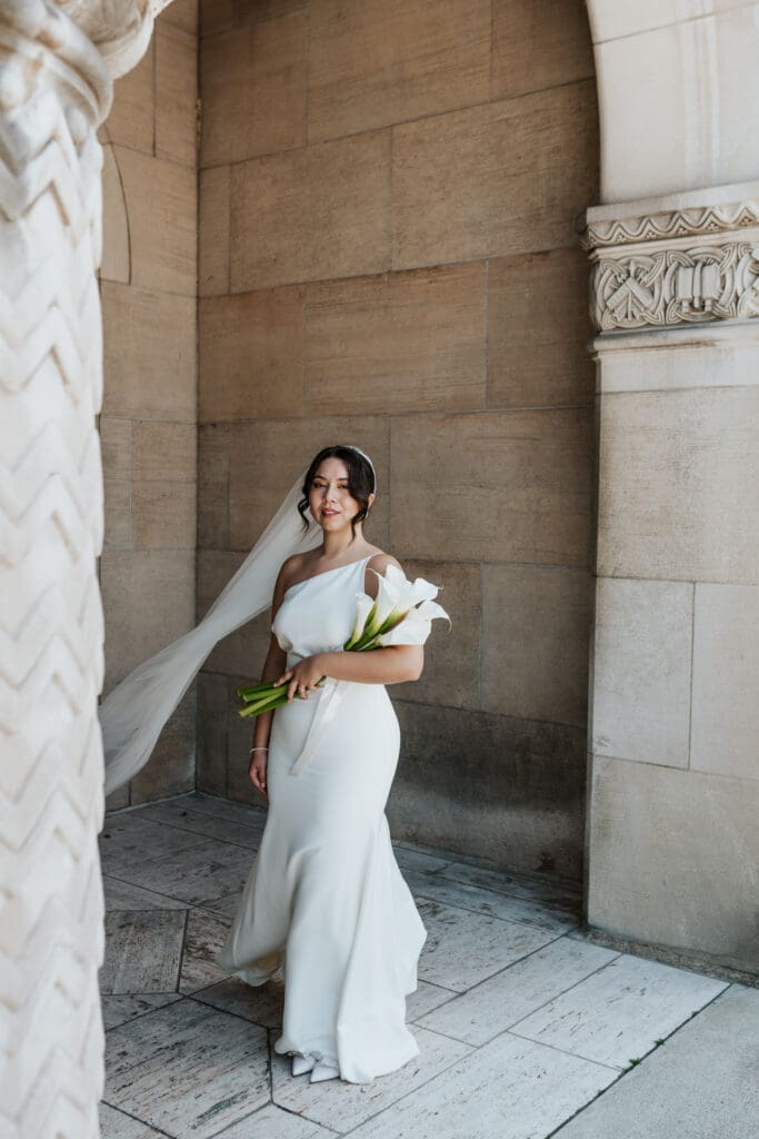 Bride standing for her portrait with her Cala lily bouquet outside of Gesu Catholic Church
