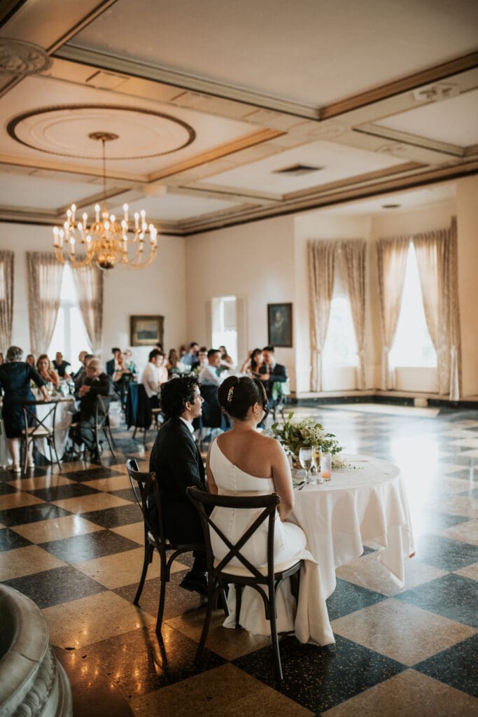 newly weds sit and listen to toasts inside the Detroit yacht club ballroom
