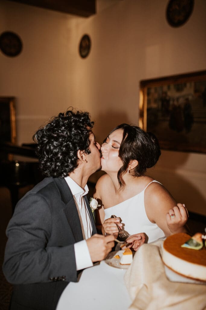 Bride and groom kiss during their cake cutting