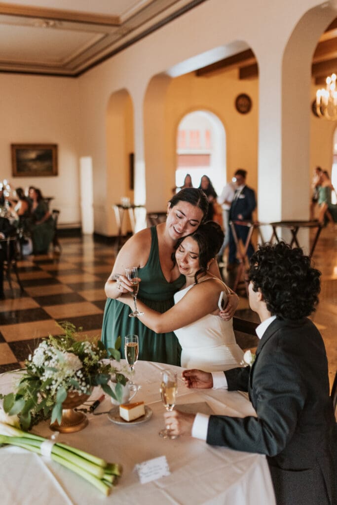 the bride receives a hug from her maid of honor after her toast in the Detroit yacht club ball room