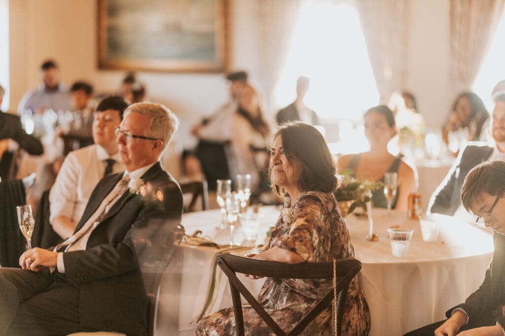 mother of the bride listens lovingly during her daughters speech for her other daughters wedding
