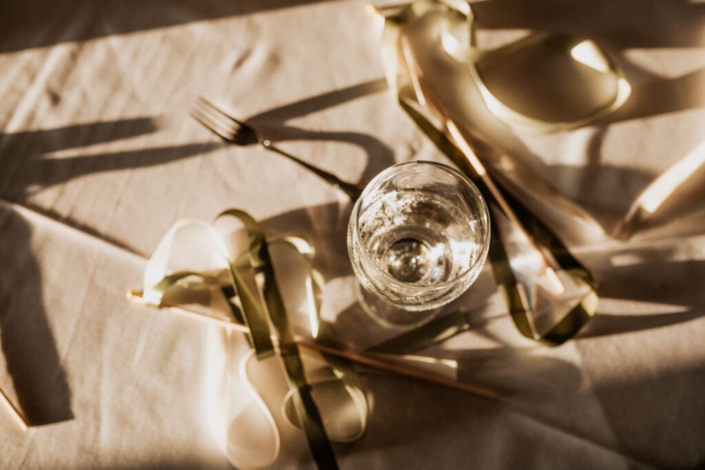 detail shot of the table with water glass and ribbon wands during sunset at the reception