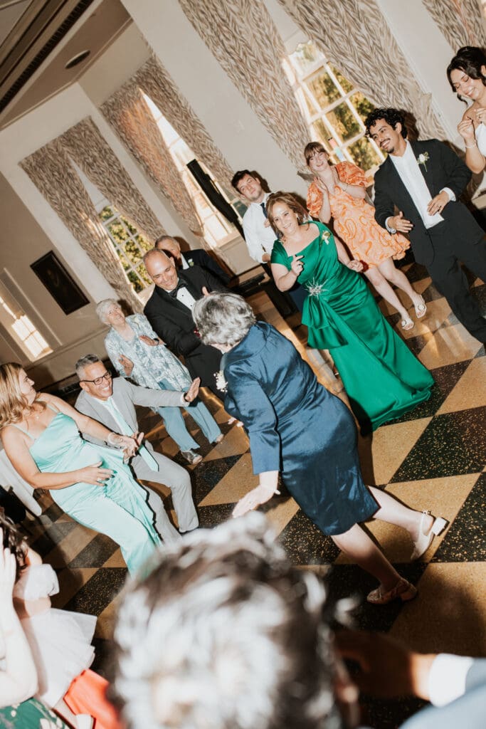 grandma of the groom dances in the middle of a dance circle during open dance at the Detroit yacht club the photographer is utilizing direct flash