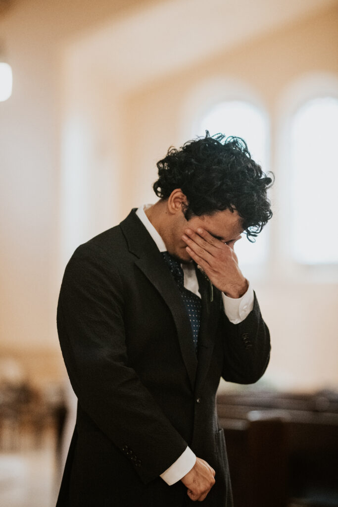 Groom crying as he watches his bride walk down the aisle inside Gesu Catholic Church in Detroit Michigan