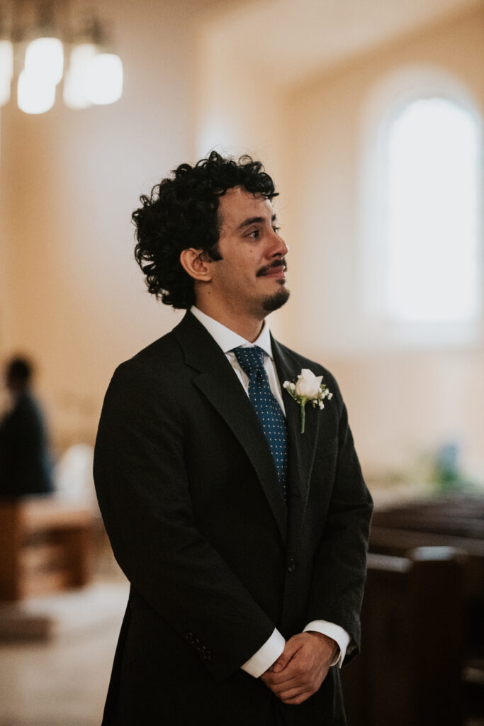 Groom crying as he watches his bride walk down the aisle inside Gesu Catholic Church in Detroit Michigan