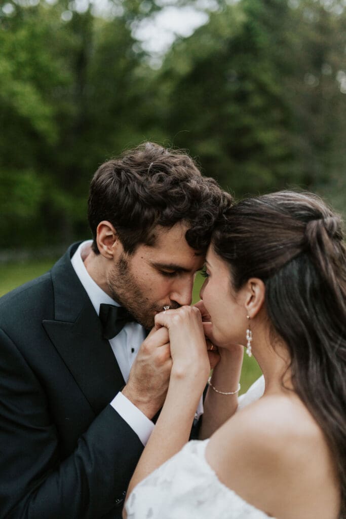 groom kissing his brides hands with their foreheads touching