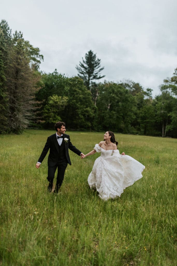 a bride and groom joyfully running together in a field 