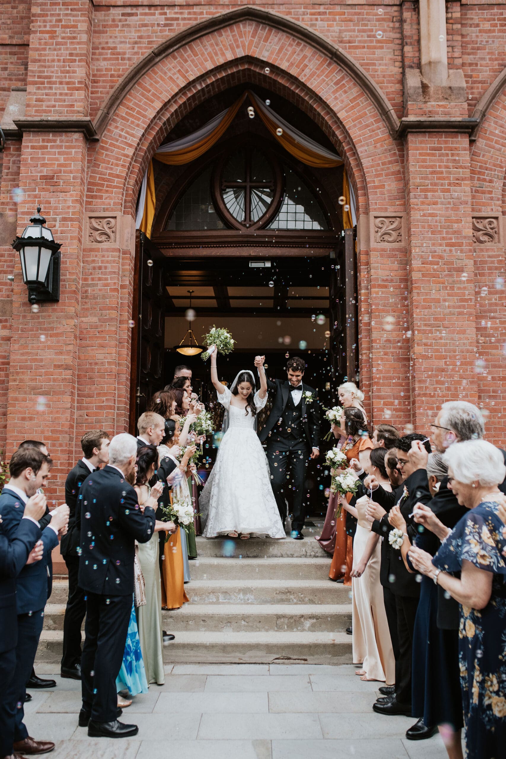 bride and groom bubble exit from a catholic wedding ceremony at St. Mary of the Assumption Parish in brookline Massachusetts