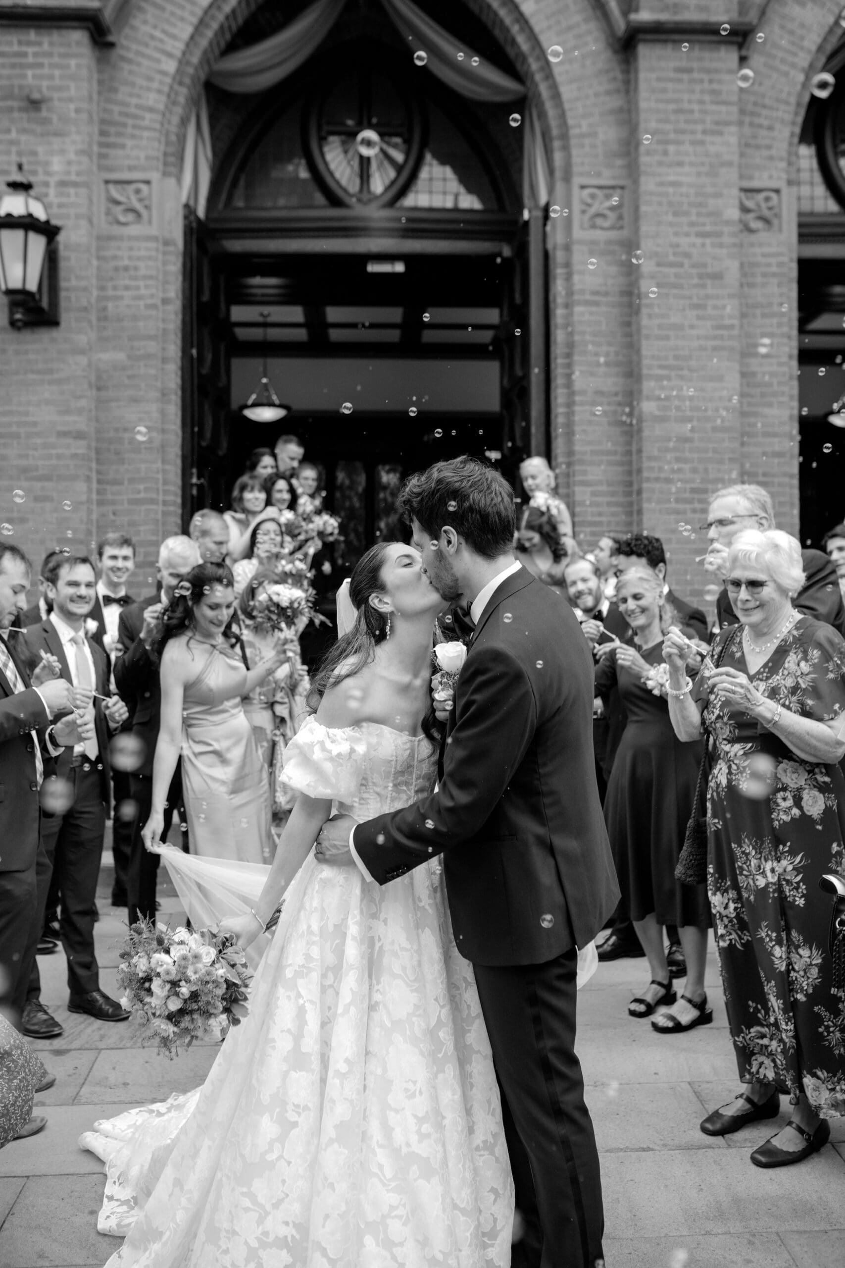 the bride and groom kissing during a bubble exit outside the catholic church in boston