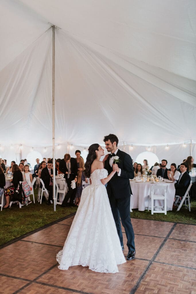 the bride and groom having their first dance in an outdoor tented reception