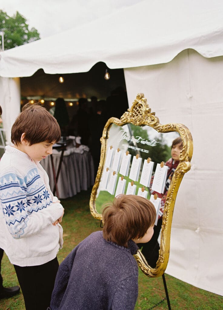 medium format film photo of bride's nephews looking at the seating chart 