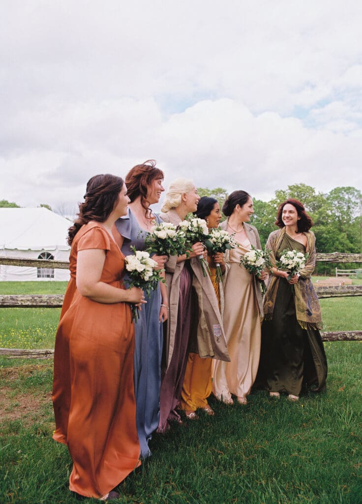 bridesmaids looking at each other and smiling in their colorful dresses shot on film