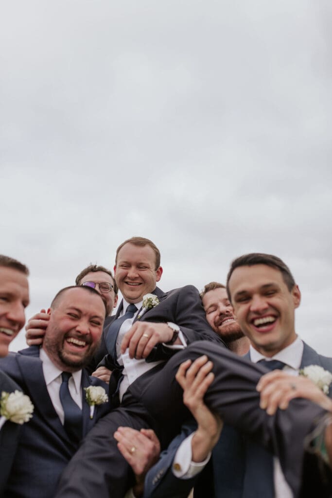 groom being picked up by his groomsmen at the atchison golf course