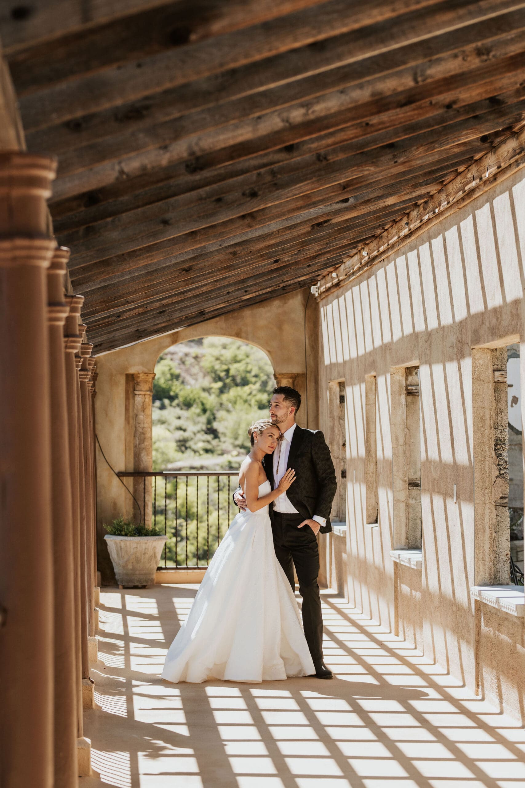 Newlyweds posing in arched corridor with dramatic light and shadow at Arizona wedding venue