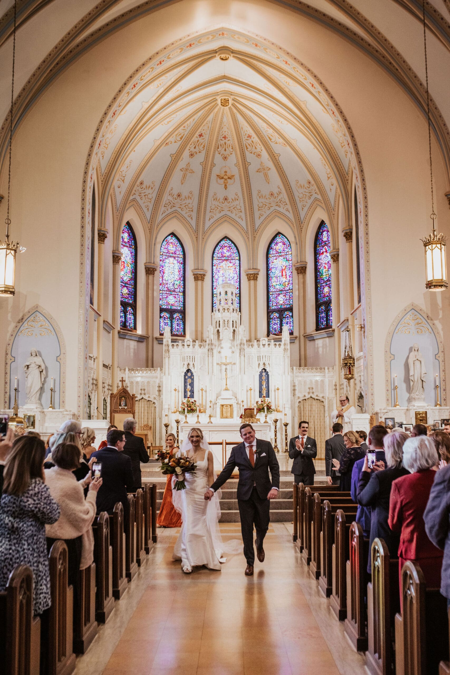 joyful newlyweds walking down the aisle after a Catholic wedding ceremony at Cathedral of St. Peter the Apostle