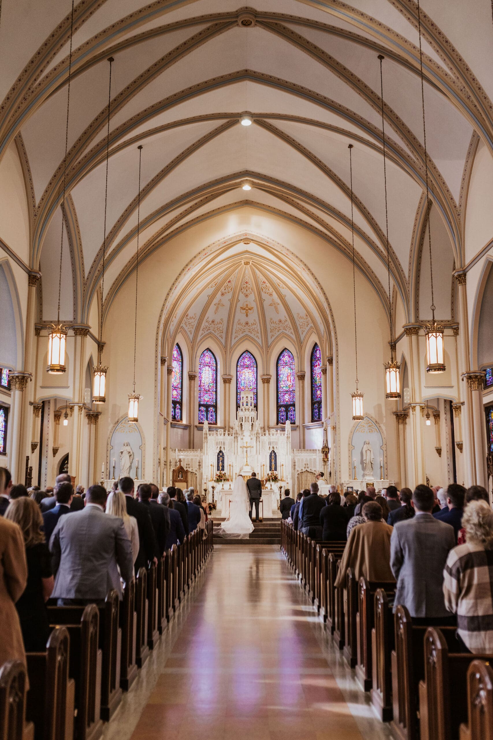wide ceremony view inside Cathedral of St. Peter the Apostle with stained glass and vaulted ceilings