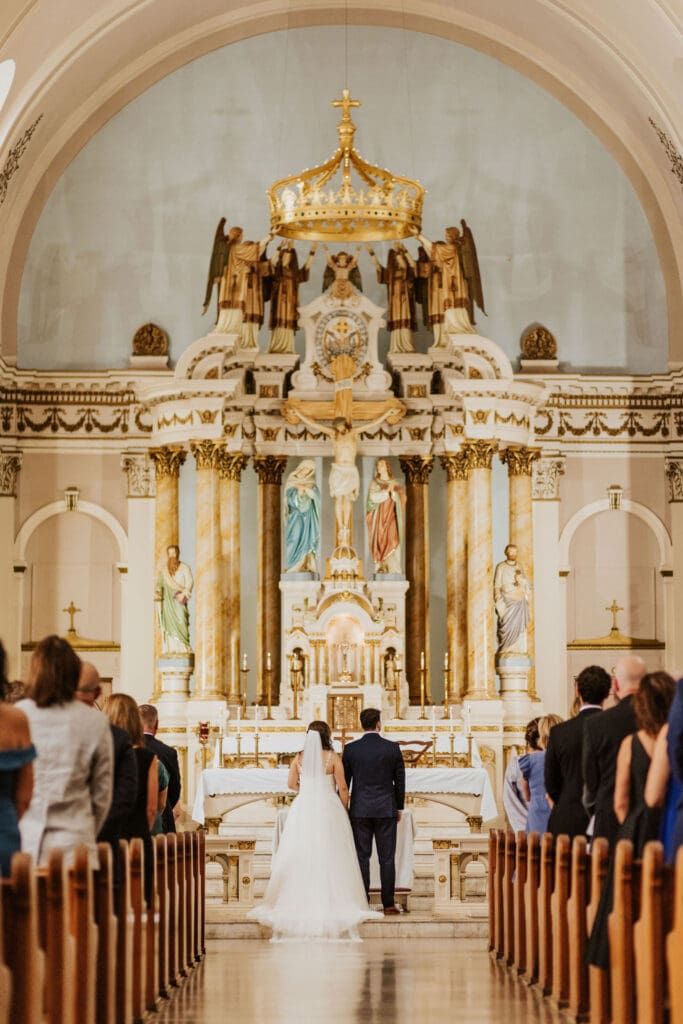 bride and groom at the altar inside Our Lady of Sorrows Catholic Church