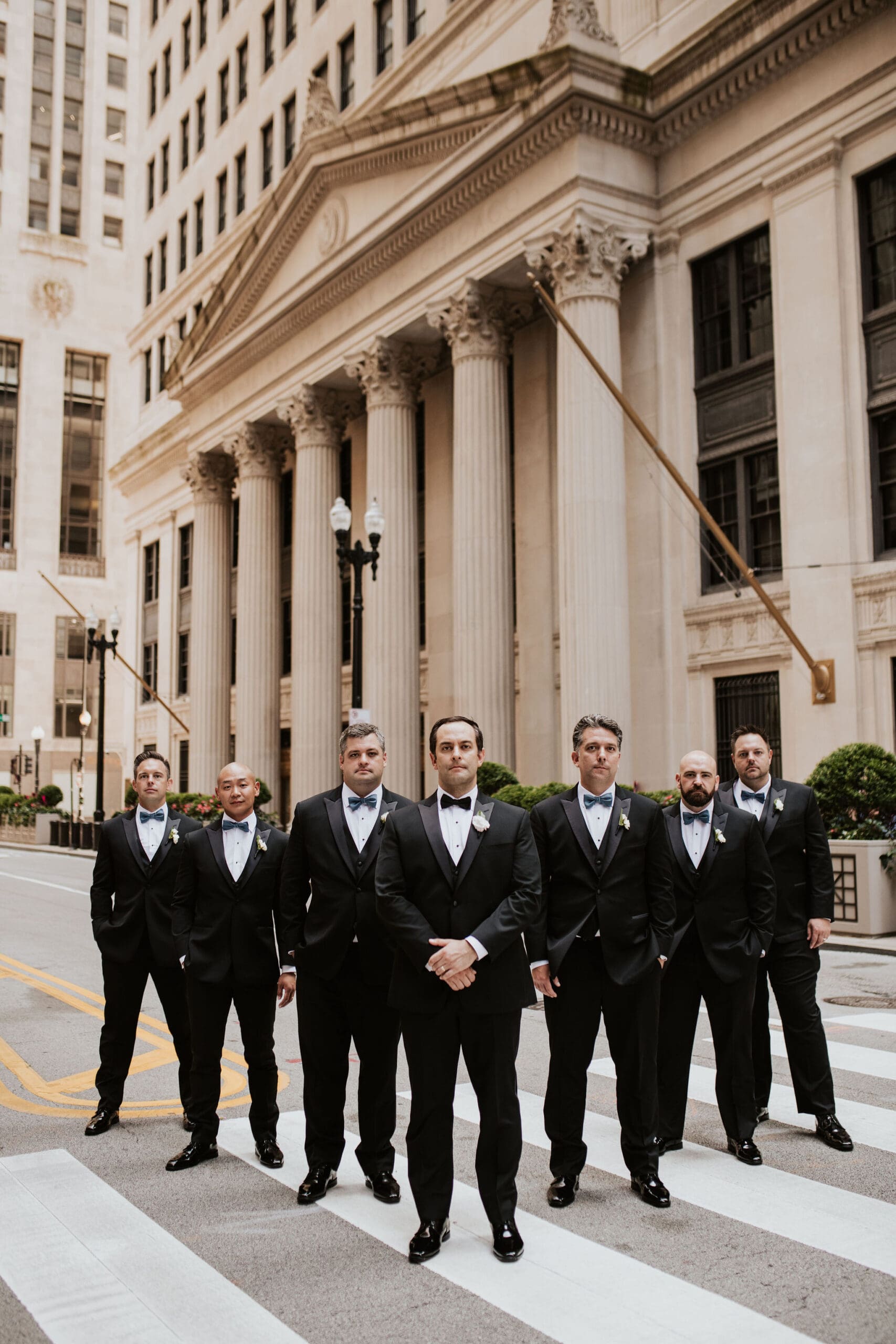 Groom and groomsmen posing in front of the Chicago Board of Trade during downtown Chicago wedding photos.