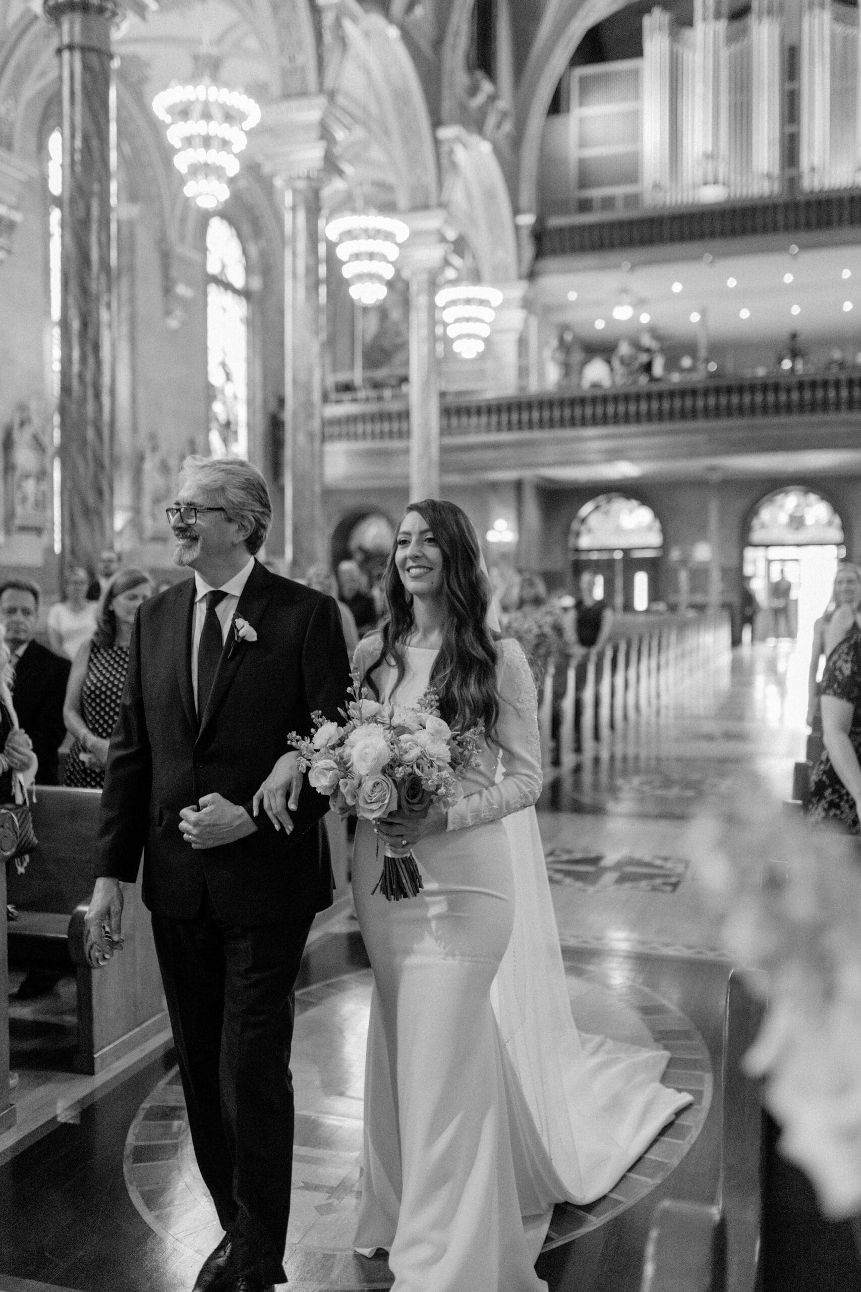 Bride walking down the aisle with her father inside Saint John Cantius Chicago wedding ceremony.