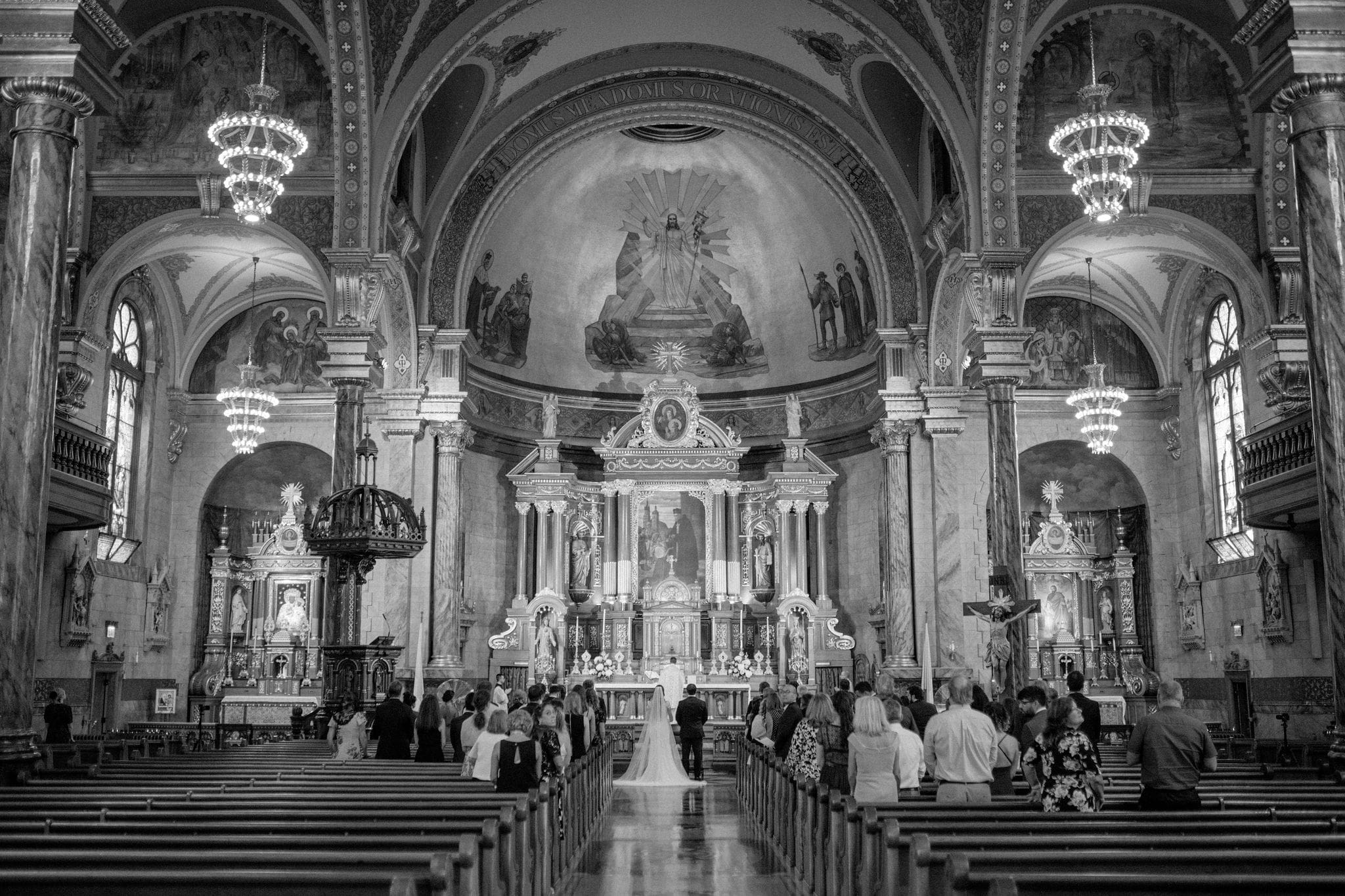 Wide black and white view of the historic interior of Saint John Cantius Chicago during wedding ceremony.