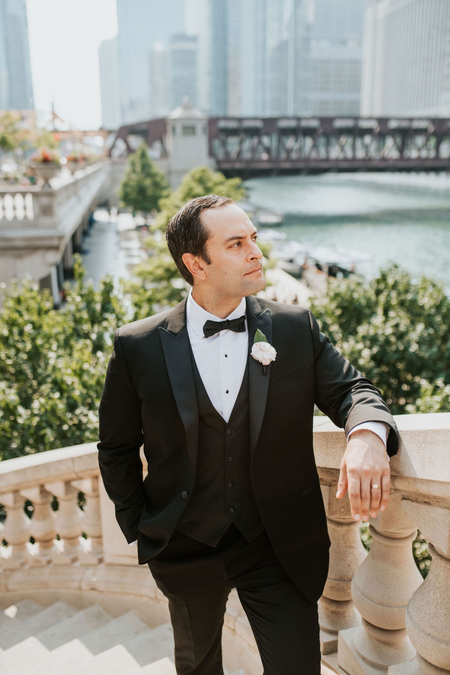Groom portrait overlooking the Chicago Riverwalk with skyline views during wedding portraits in downtown Chicago.