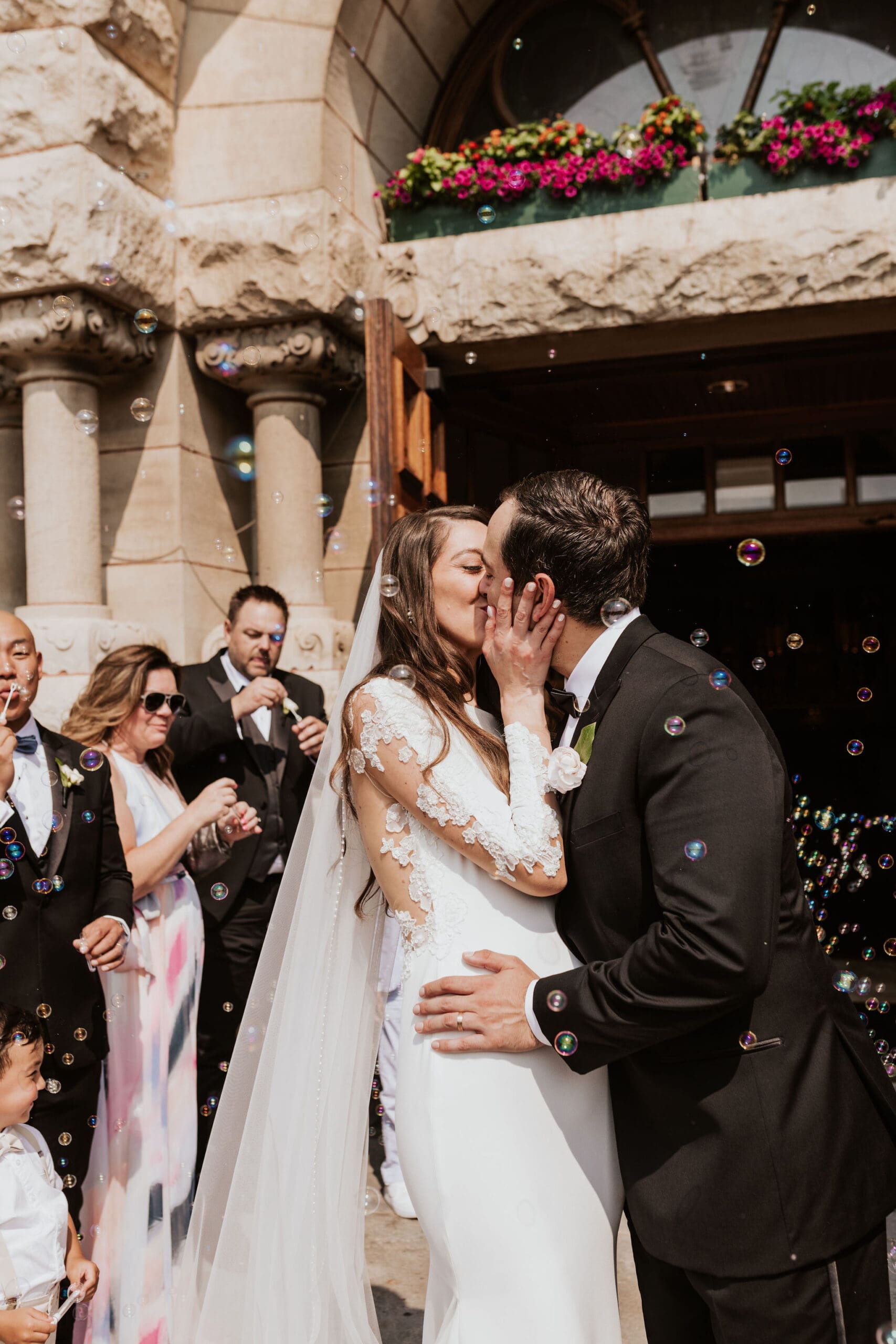 Bride and groom kissing outside Saint John Cantius Chicago church during joyful wedding exit.