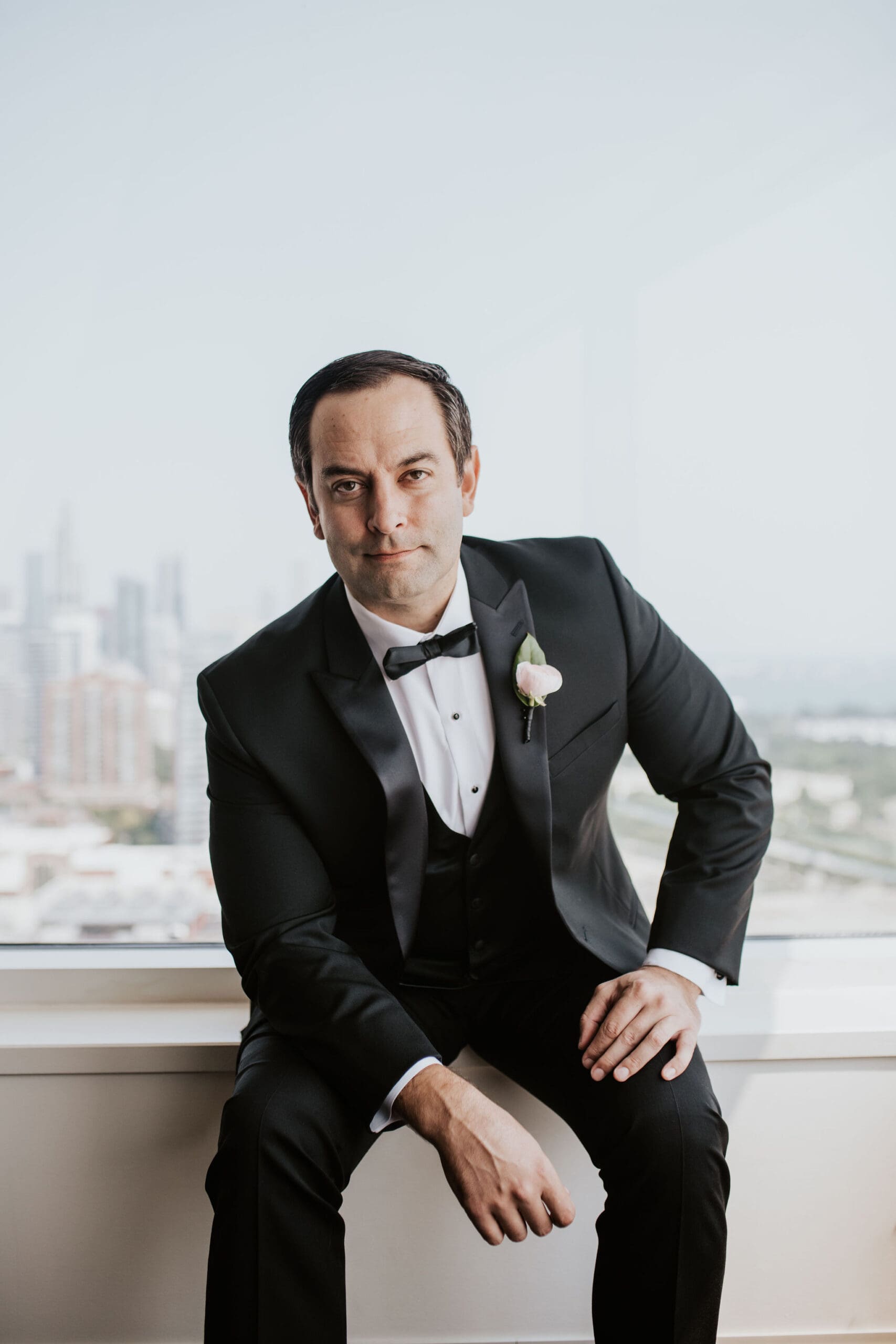 Portrait of groom in black tuxedo with Chicago skyline view during wedding day.