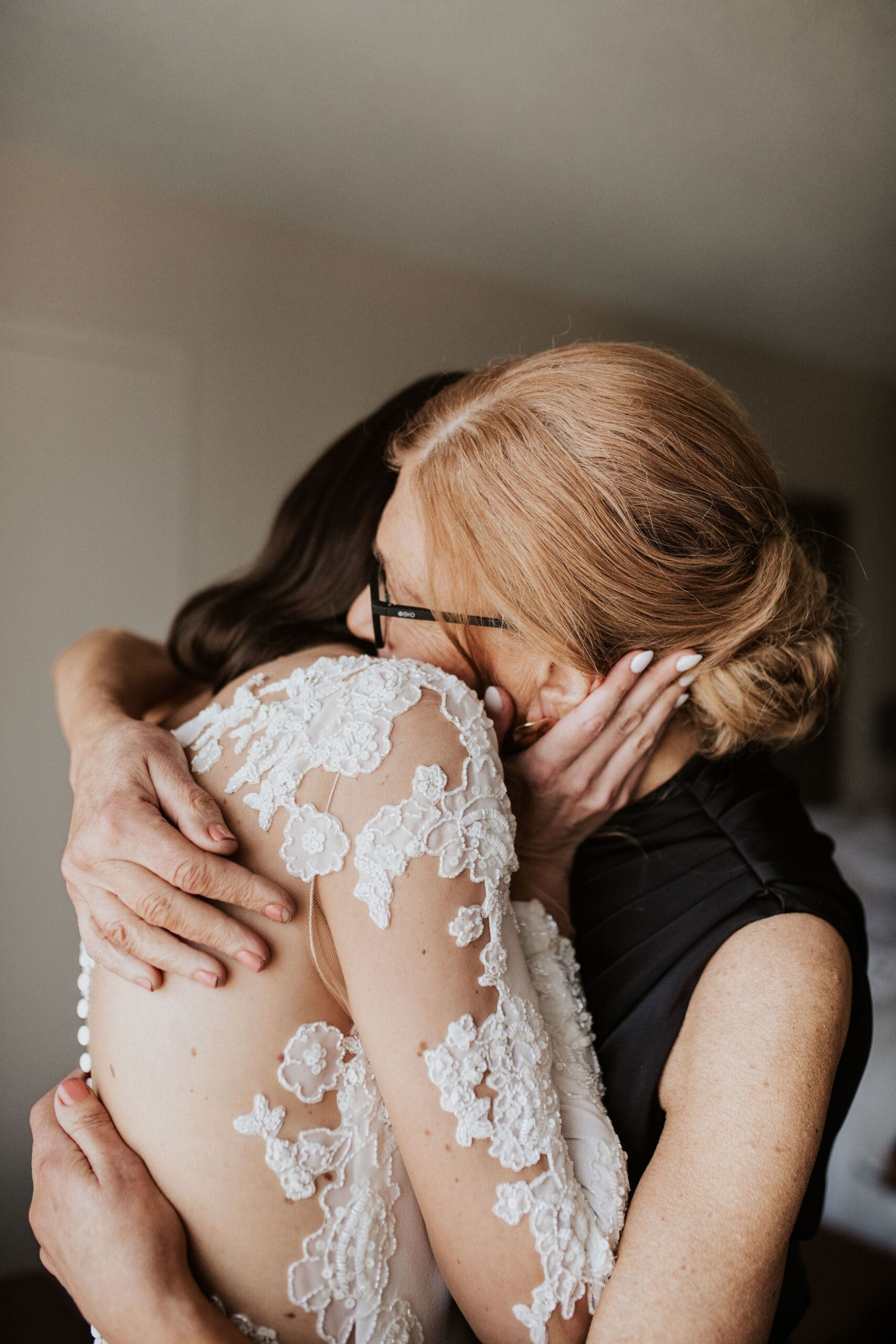Bride hugging her mother during emotional wedding morning moment.