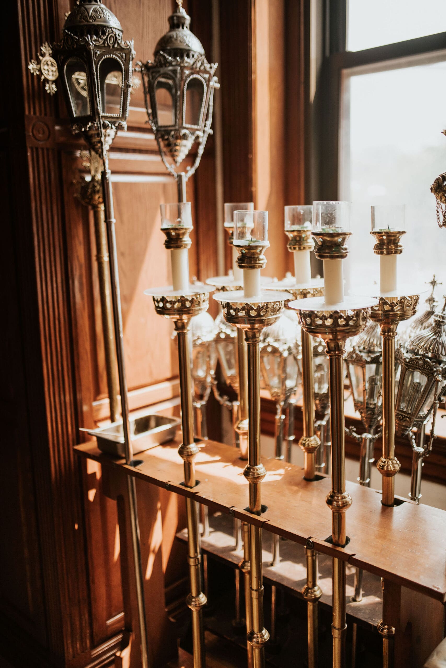Gold votive candle stands inside Saint John Cantius Chicago church near window light.