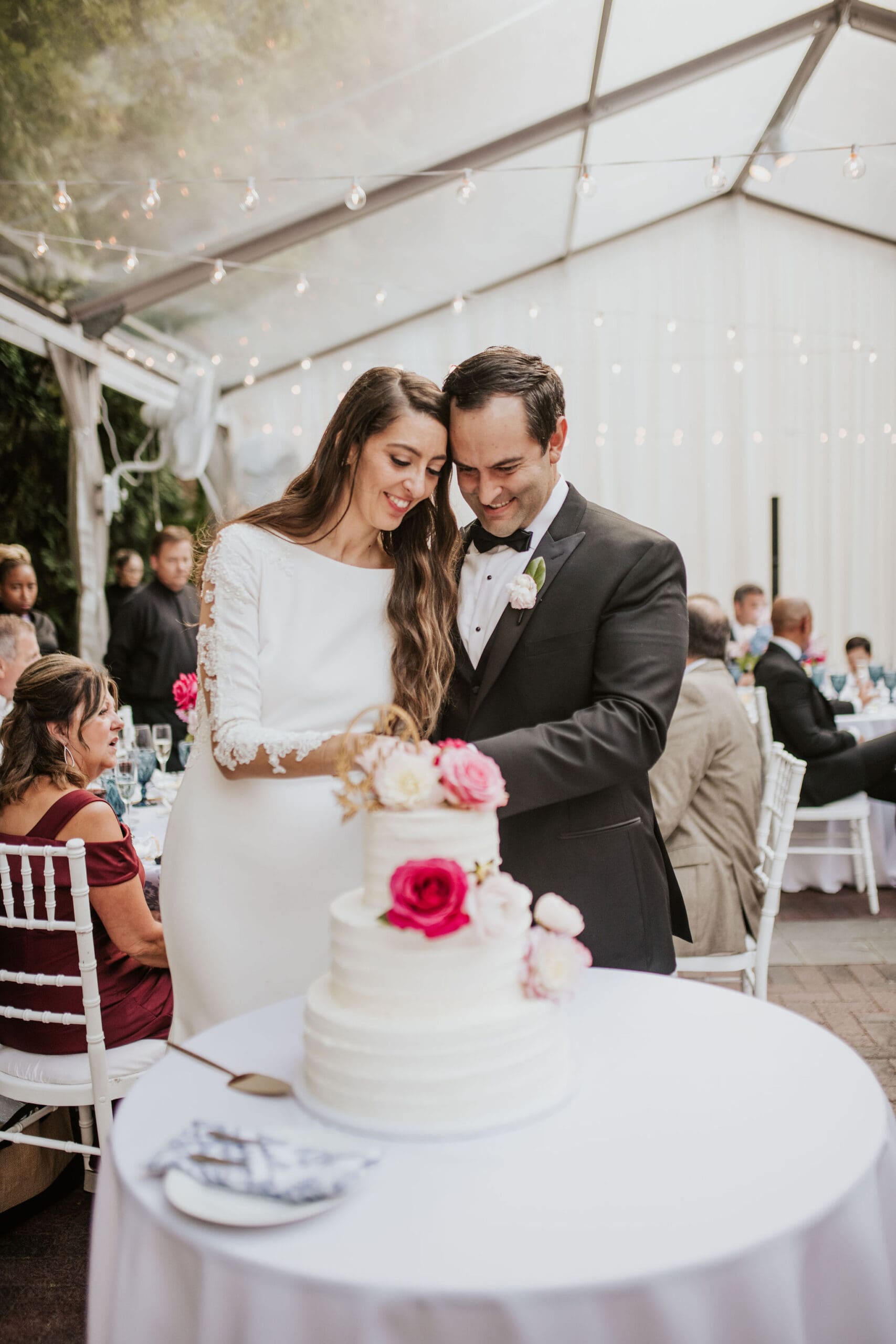 Bride and groom cutting wedding cake during reception celebration.