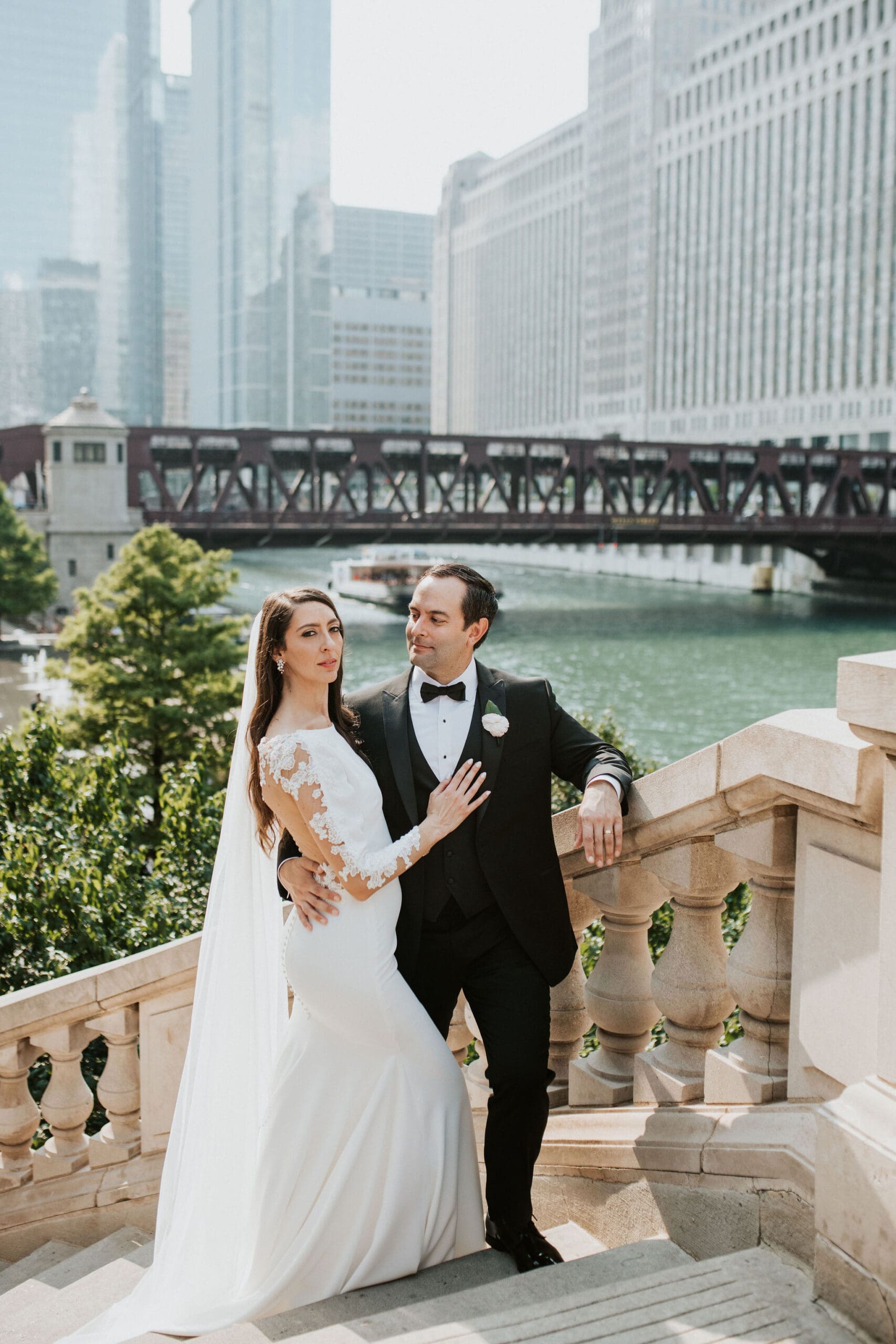 Bride and groom posing for Chicago Riverwalk wedding portraits with skyline view.