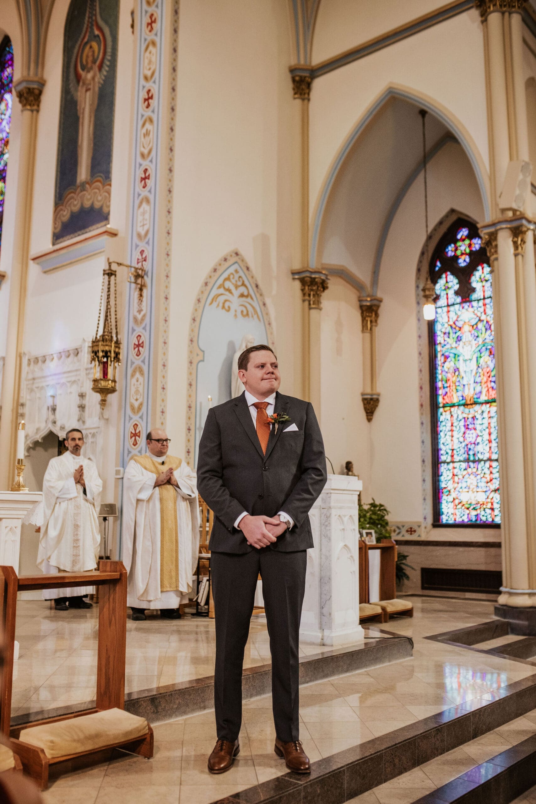 Groom waiting at the altar inside a Kansas City Catholic church with stained glass windows and elegant cathedral architecture