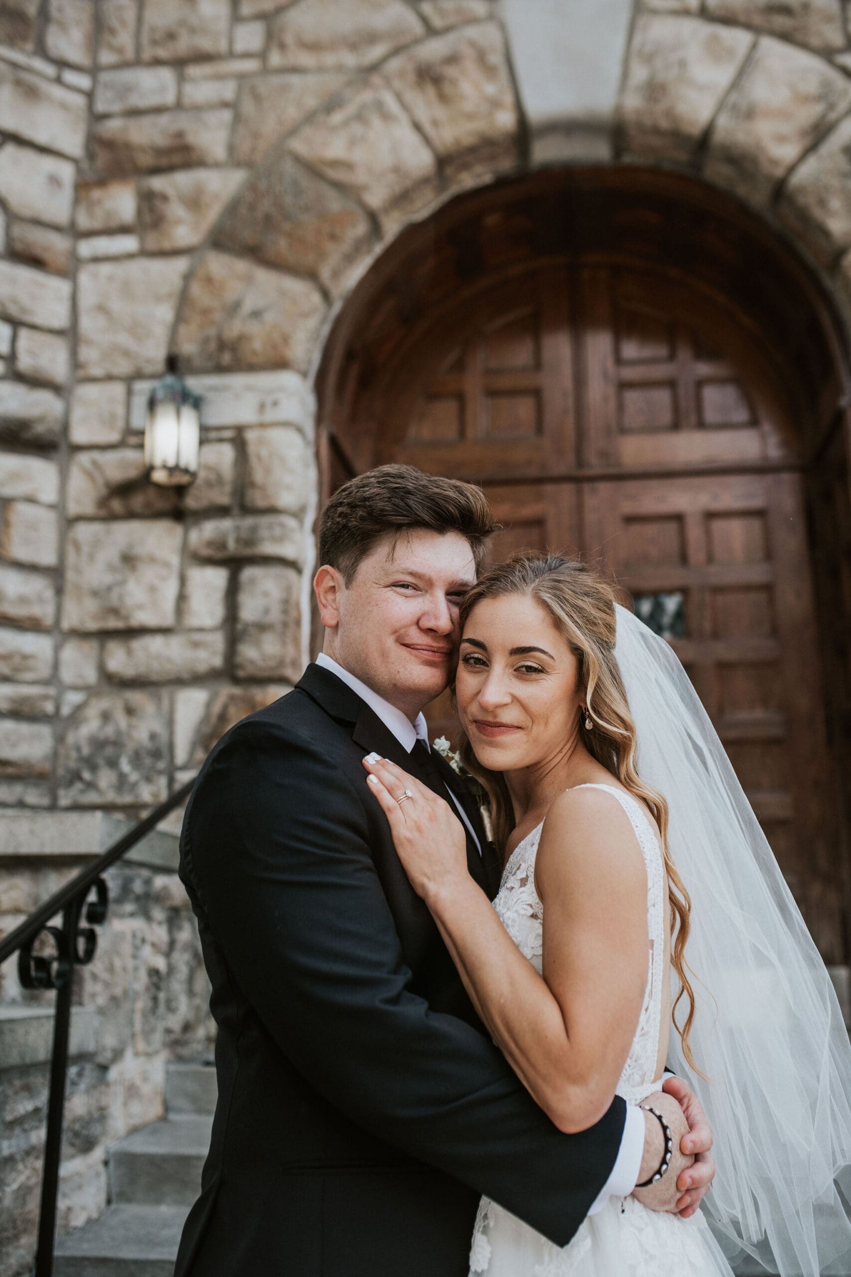 Romantic portrait of newlyweds outside a Kansas City Catholic church with historic stone architecture