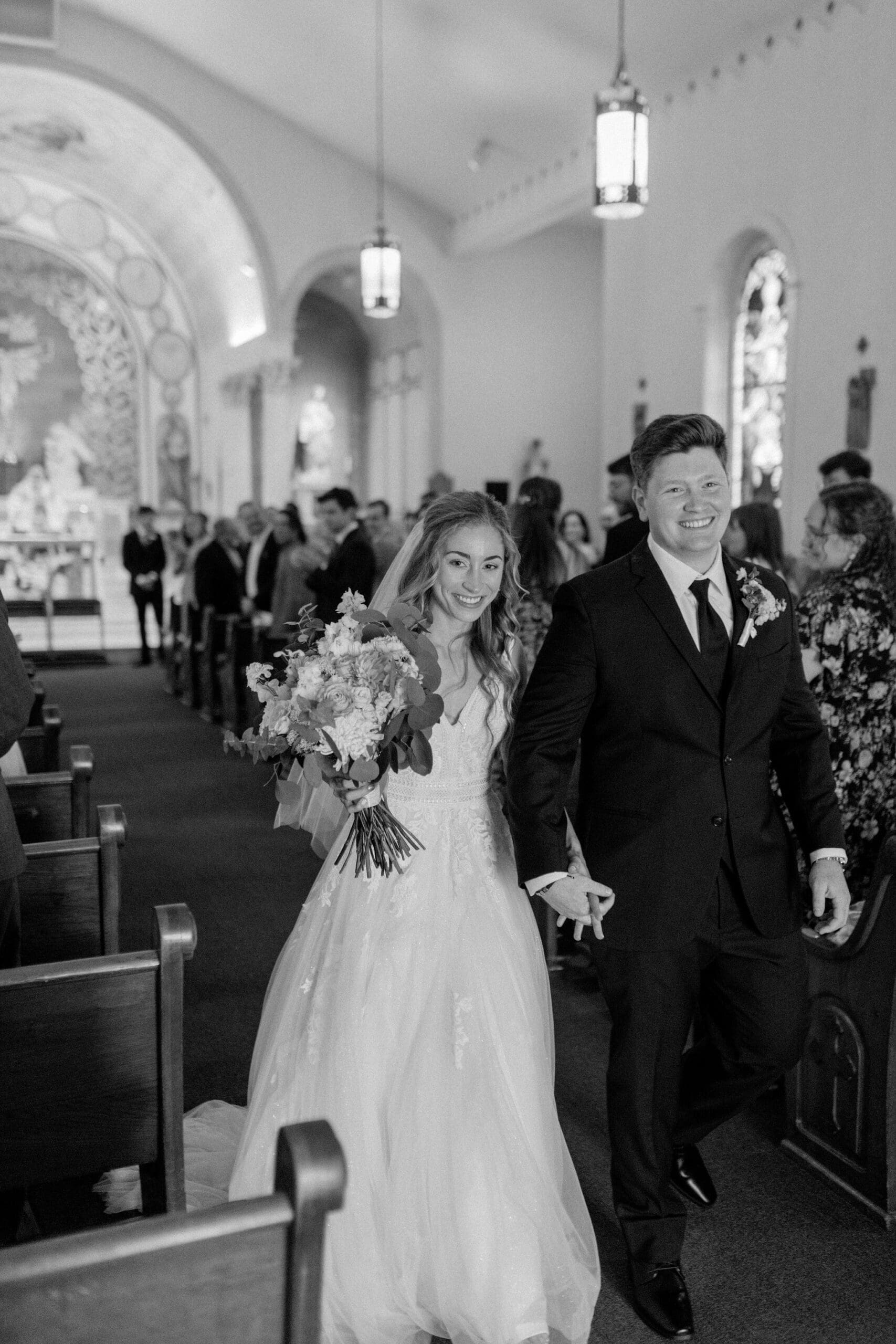 Bride and groom exit Holy Trinity Stone Chapel after their wedding ceremony in lenexa kansas