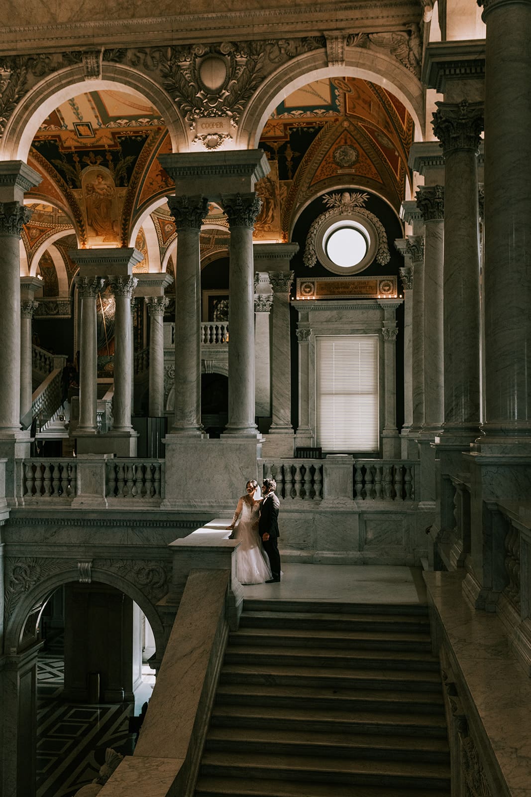 A couple standing inside the library of congress grand hall taking wedding portraits