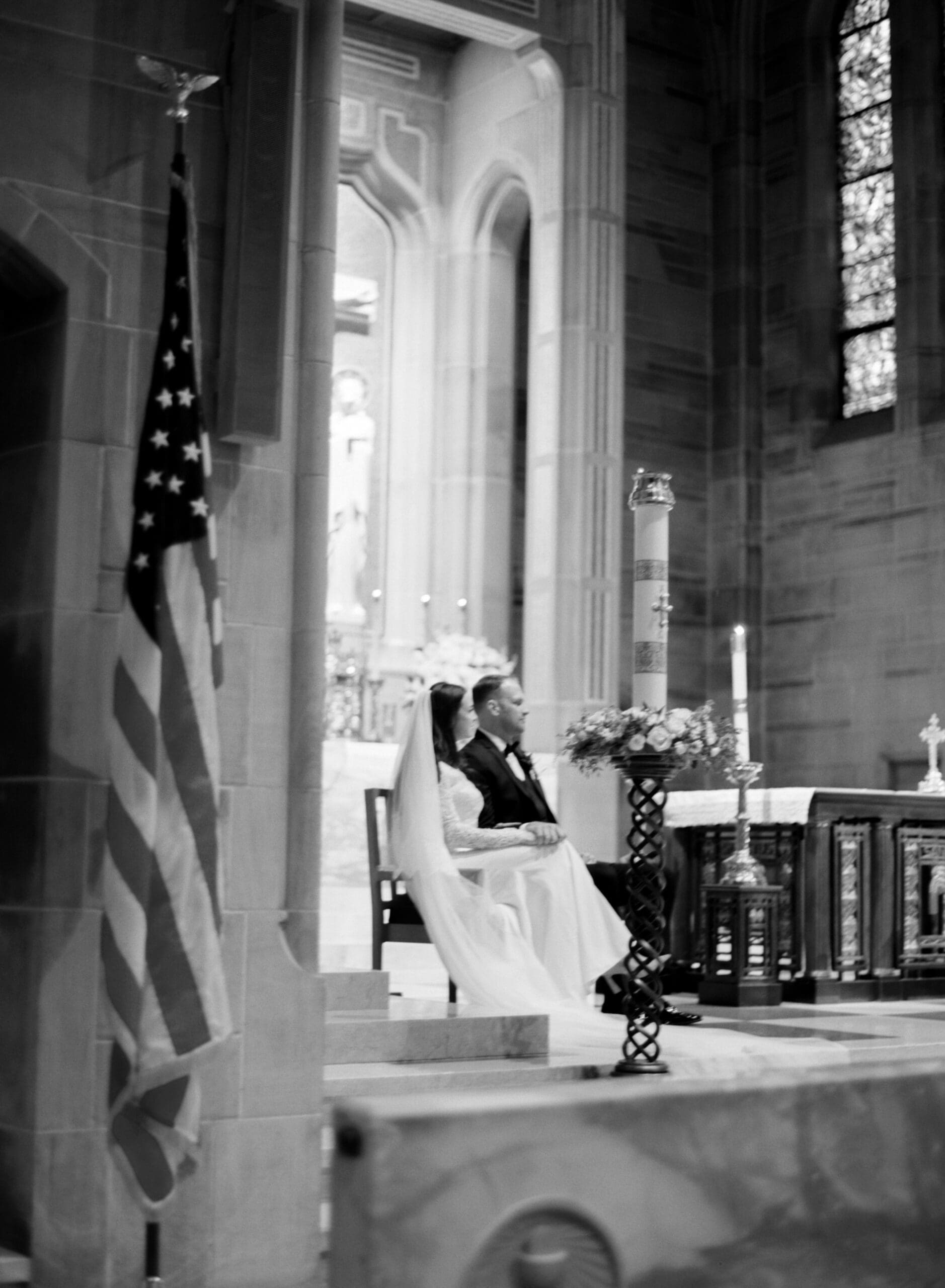 Catholic wedding ceremony inside grand church with bride and groom seated at altar during mass