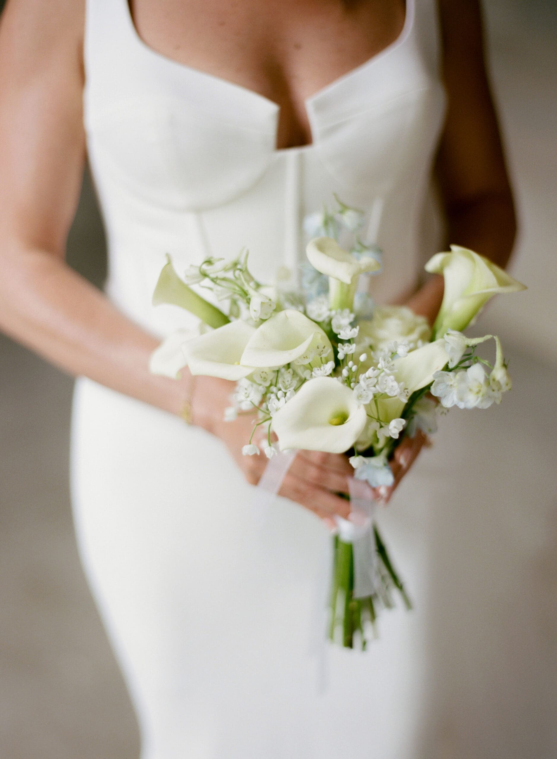 Minimal bridal bouquet with white calla lilies and soft blue florals for elegant wedding inspiration