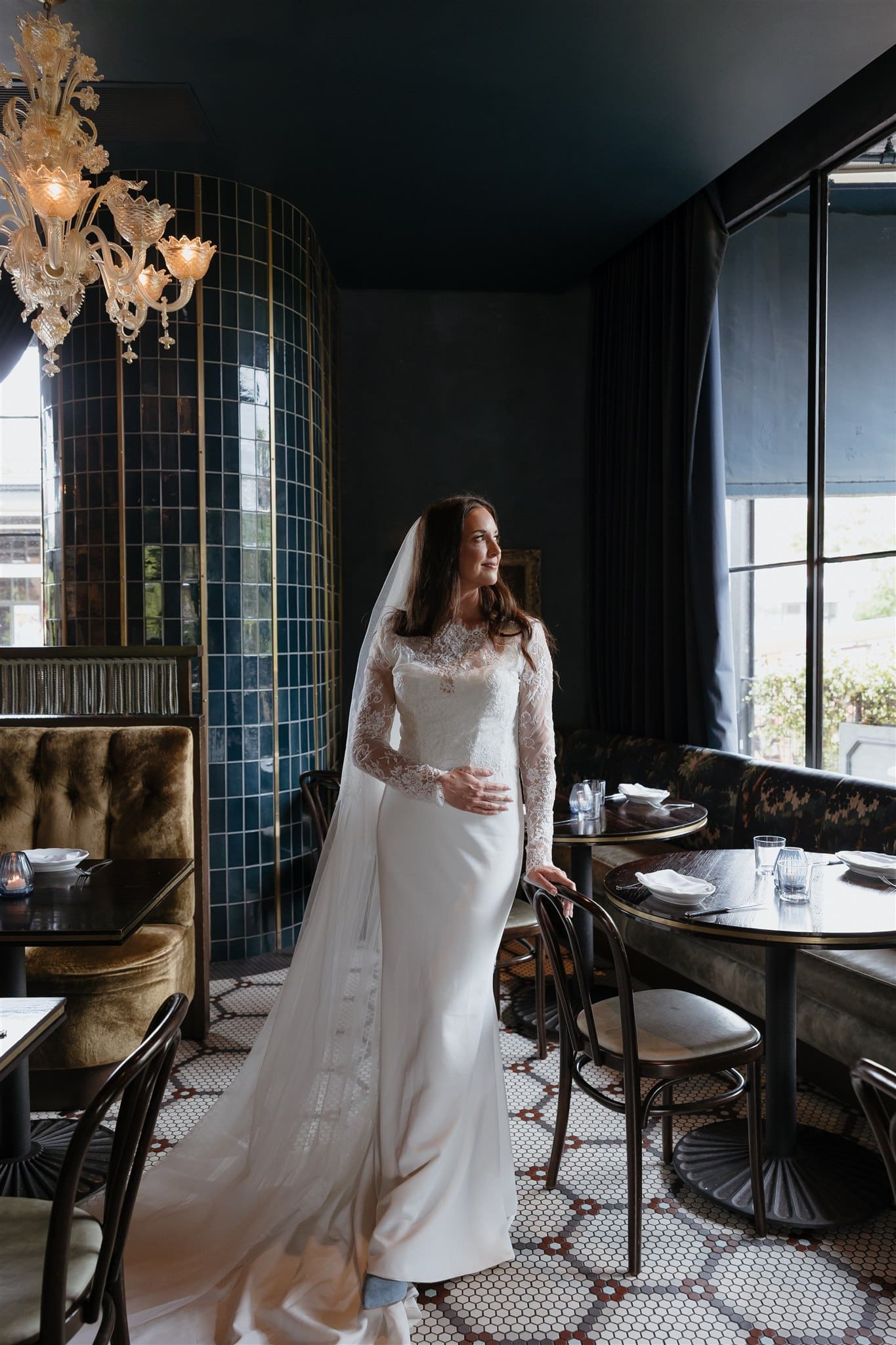 Bride standing inside stylish wedding reception venue with dramatic lighting and timeless bridal fashion