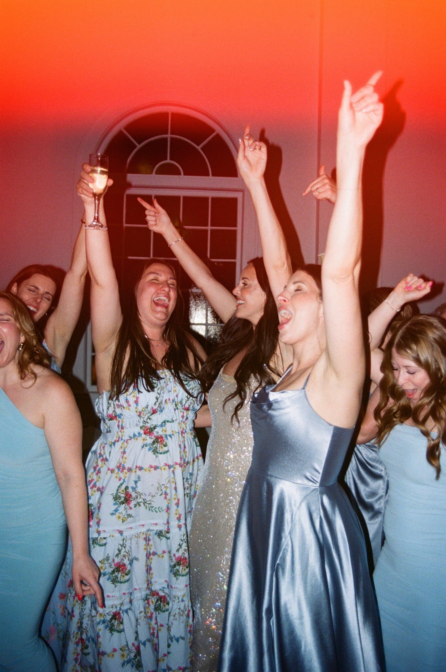 Bridesmaids dancing during lively wedding reception celebration with colorful party lighting