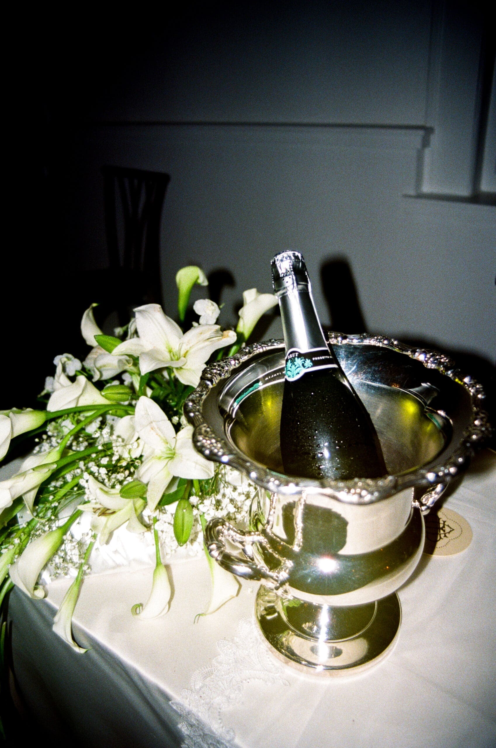 Champagne bottle and white floral wedding reception details styled by Little Flower Event Co