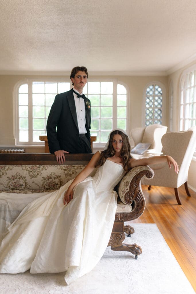 Editorial wedding portrait of the couple sitting together on a vintage couch inside the historic upstairs bedroom at Longview Mansion.