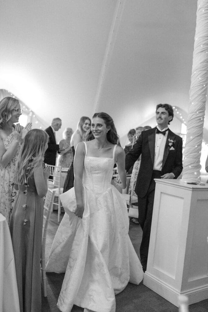 Bride and groom smiling during their wedding reception grand entrance into the beautifully lit Pavilion at Longview Mansion.