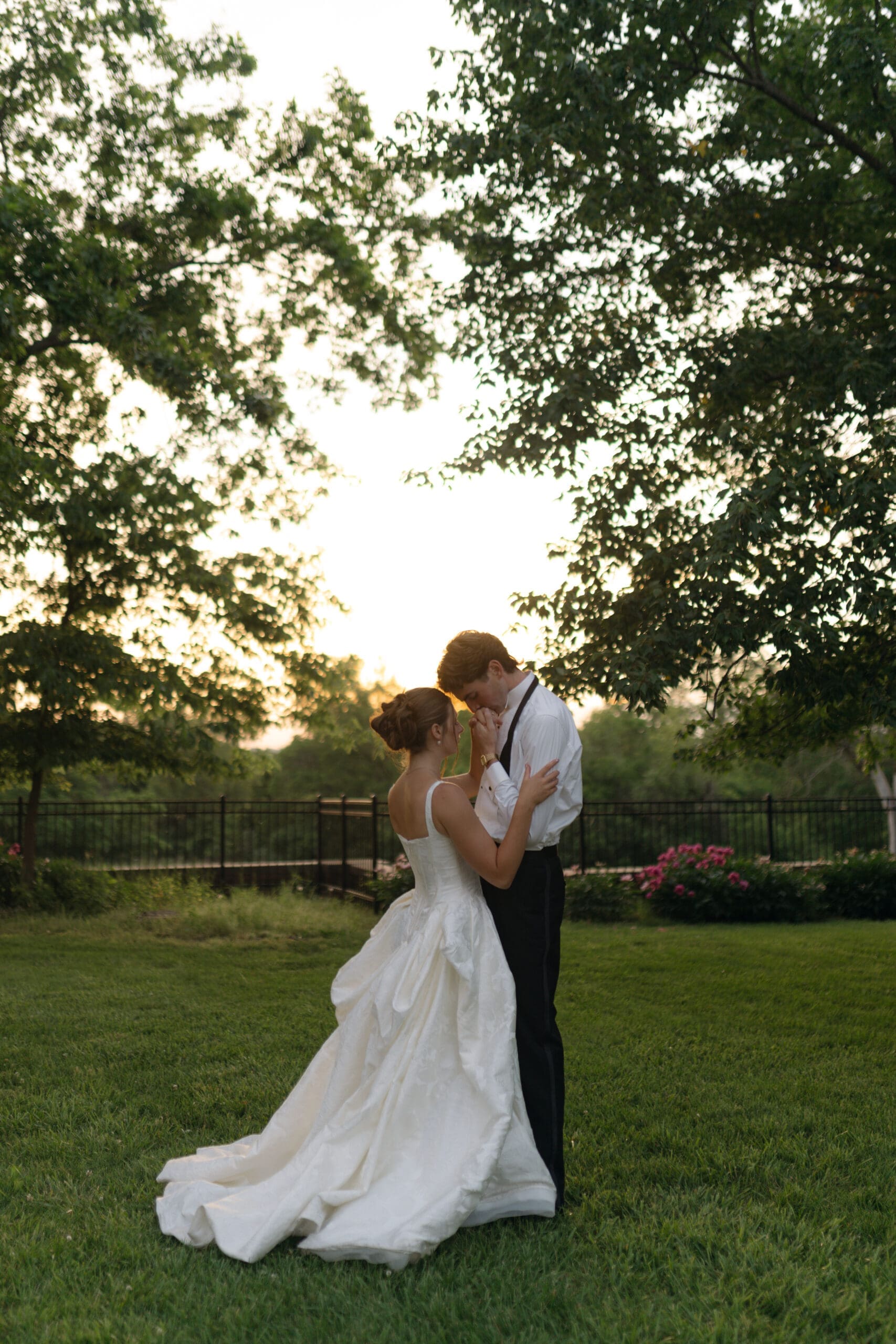 Intimate sunset wedding portrait of the bride and groom looking at each other while resting on the grass grounds of Longview Mansion.