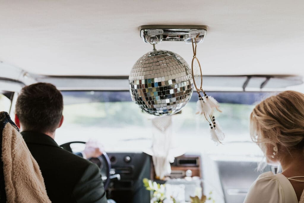 Bride and groom leaving Holy Trinity Catholic Church in a converted travel van after their wedding